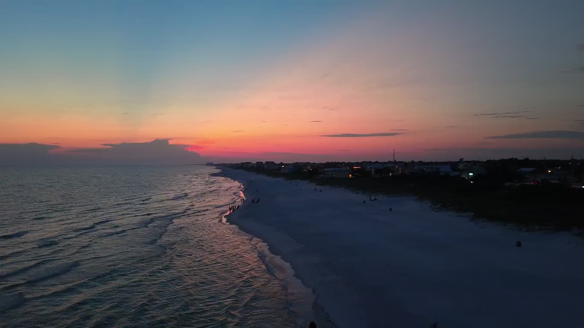 Surf line leading into the sunset along a shoreline at dusk